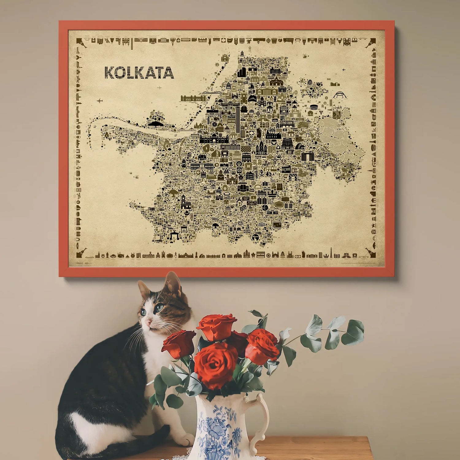 Framed map of Kolkata above a cat and vase with flowers on a table.