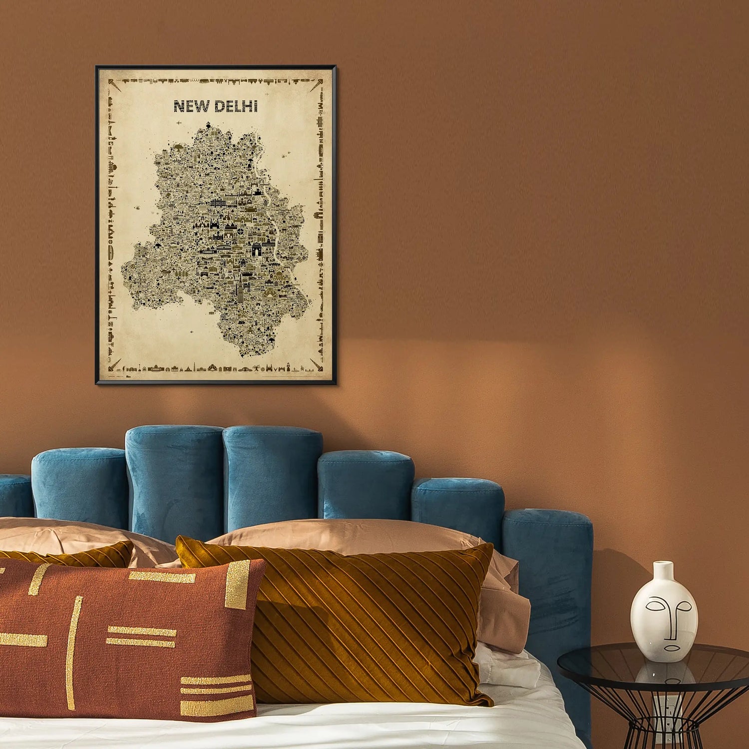 Framed map of New Delhi on a wall above a blue sofa with decorative pillows.