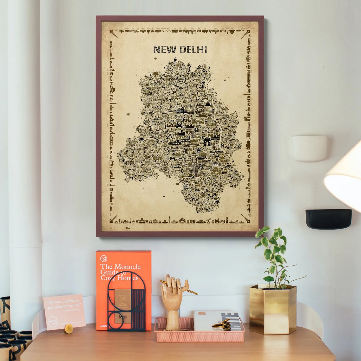 Framed map of New Delhi on a wall above a desk with decor items.