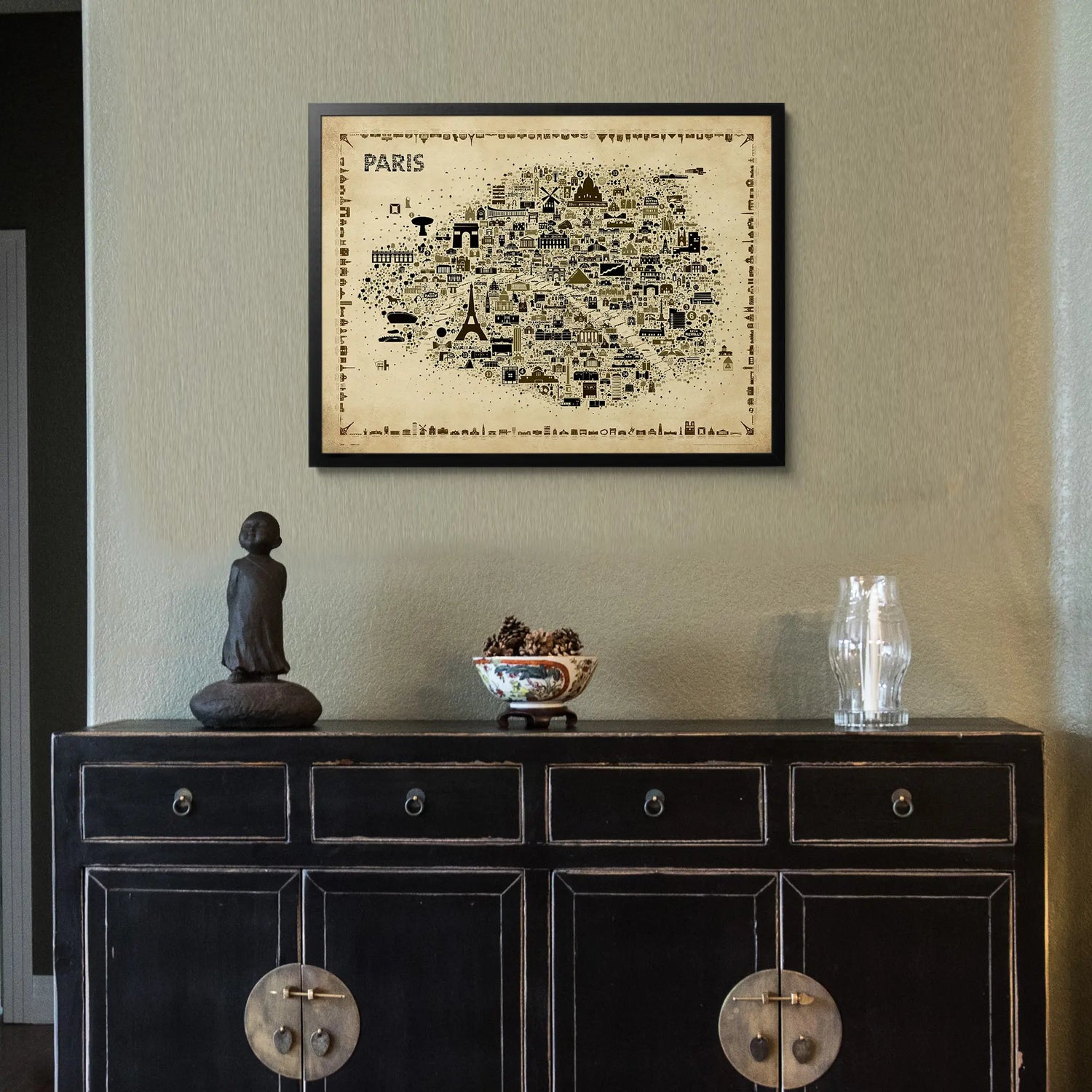 Framed map of Paris above a dark wooden cabinet with decorative items.