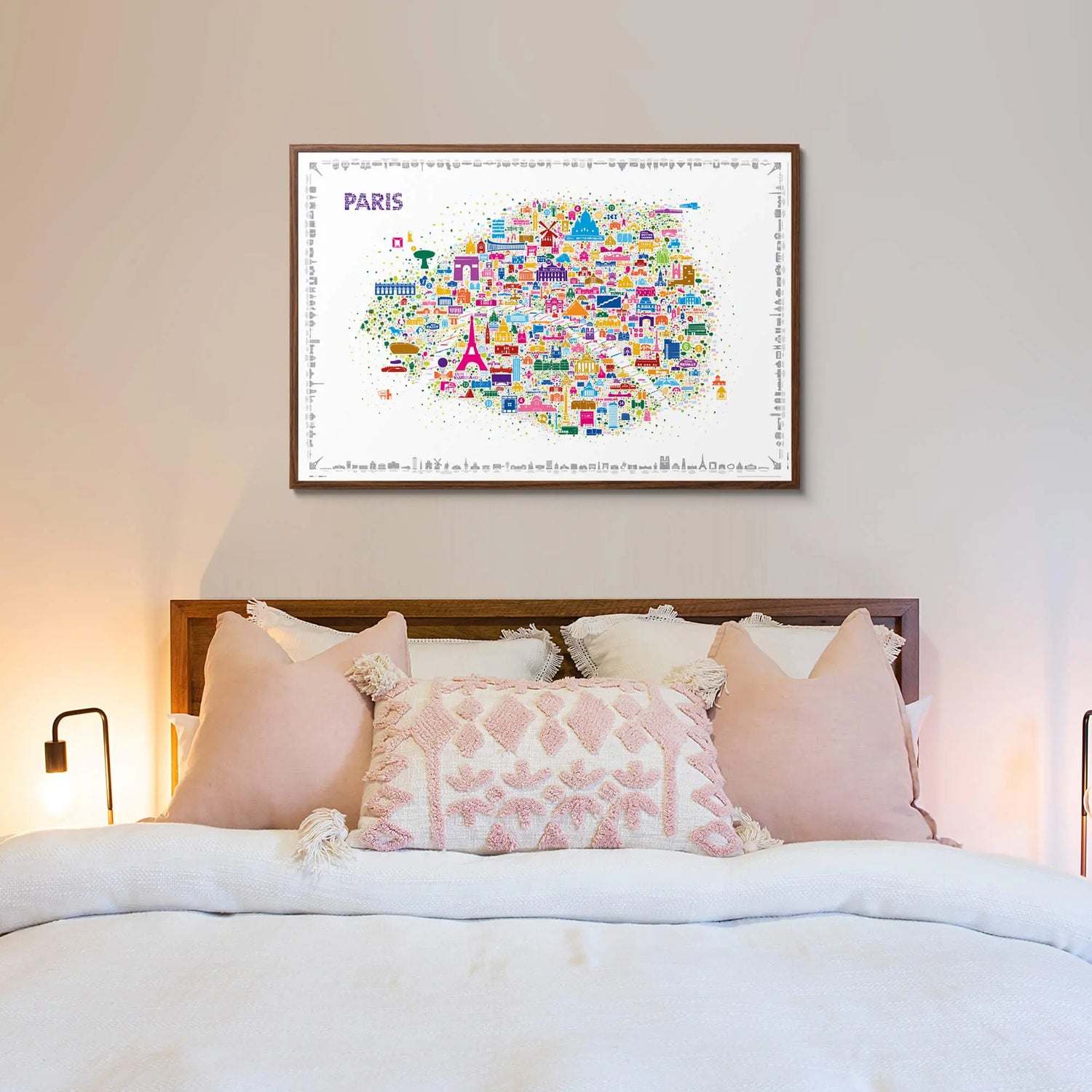 Framed map of Paris on a wall above a bed with pink bedding.