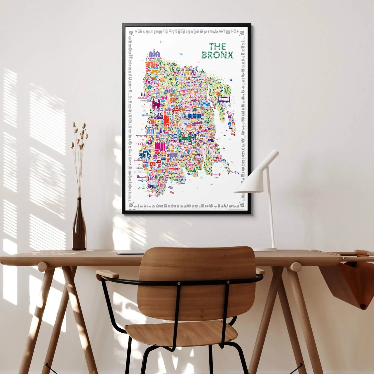 Colorful map of The Bronx on a wall above a wooden desk with a chair.
