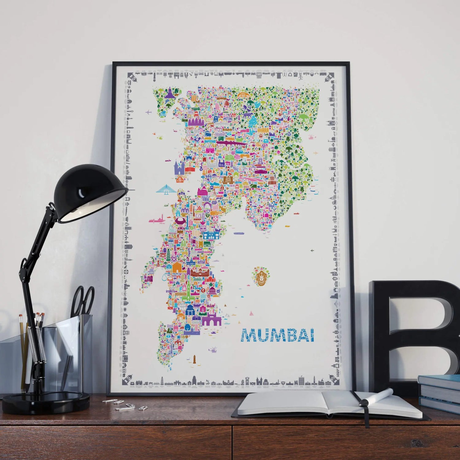 Framed map of Mumbai on a desk with a lamp and books.