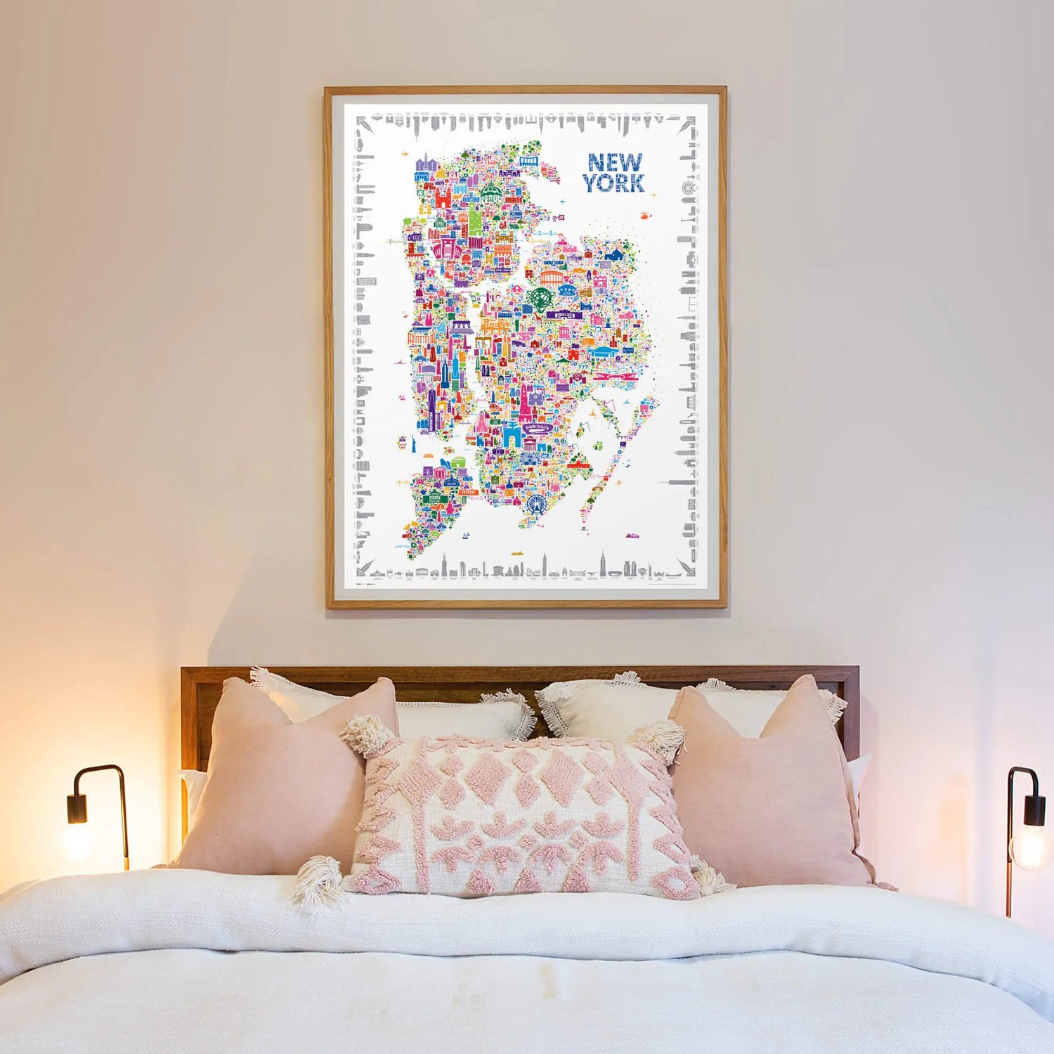 Framed map of New York on a wall above a bed with decorative pillows.