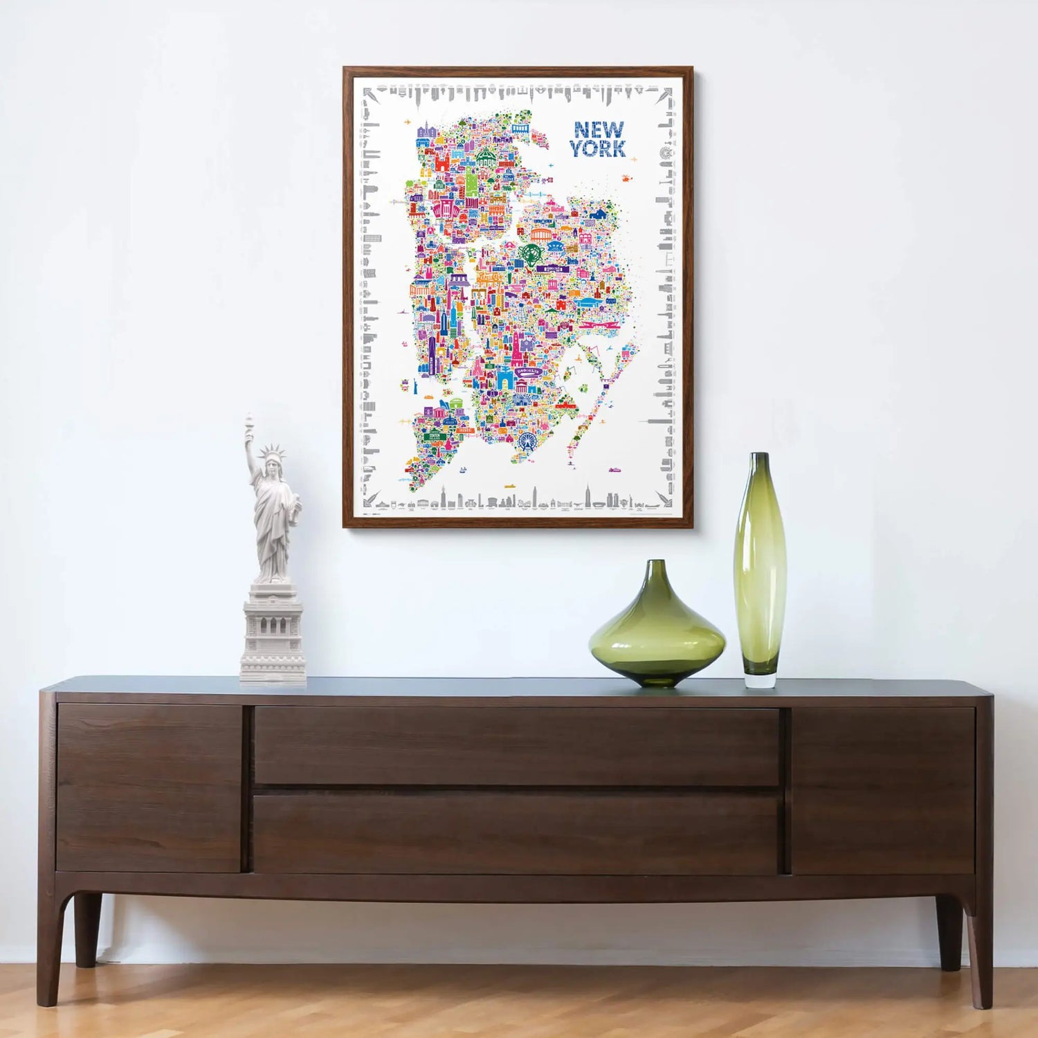 Framed Alfalfa New York illustrated map poster of New York City hanging above a modern wooden console with decorative vases and a Statue of Liberty sculpture.