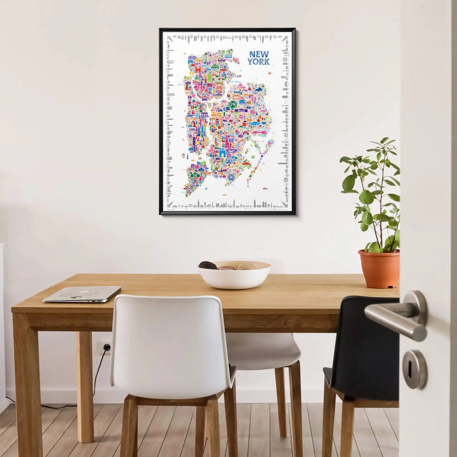 Framed Alfalfa New York illustrated map poster of New York City hanging on a white wall above a minimalist wooden dining table with modern chairs and a potted plant.
