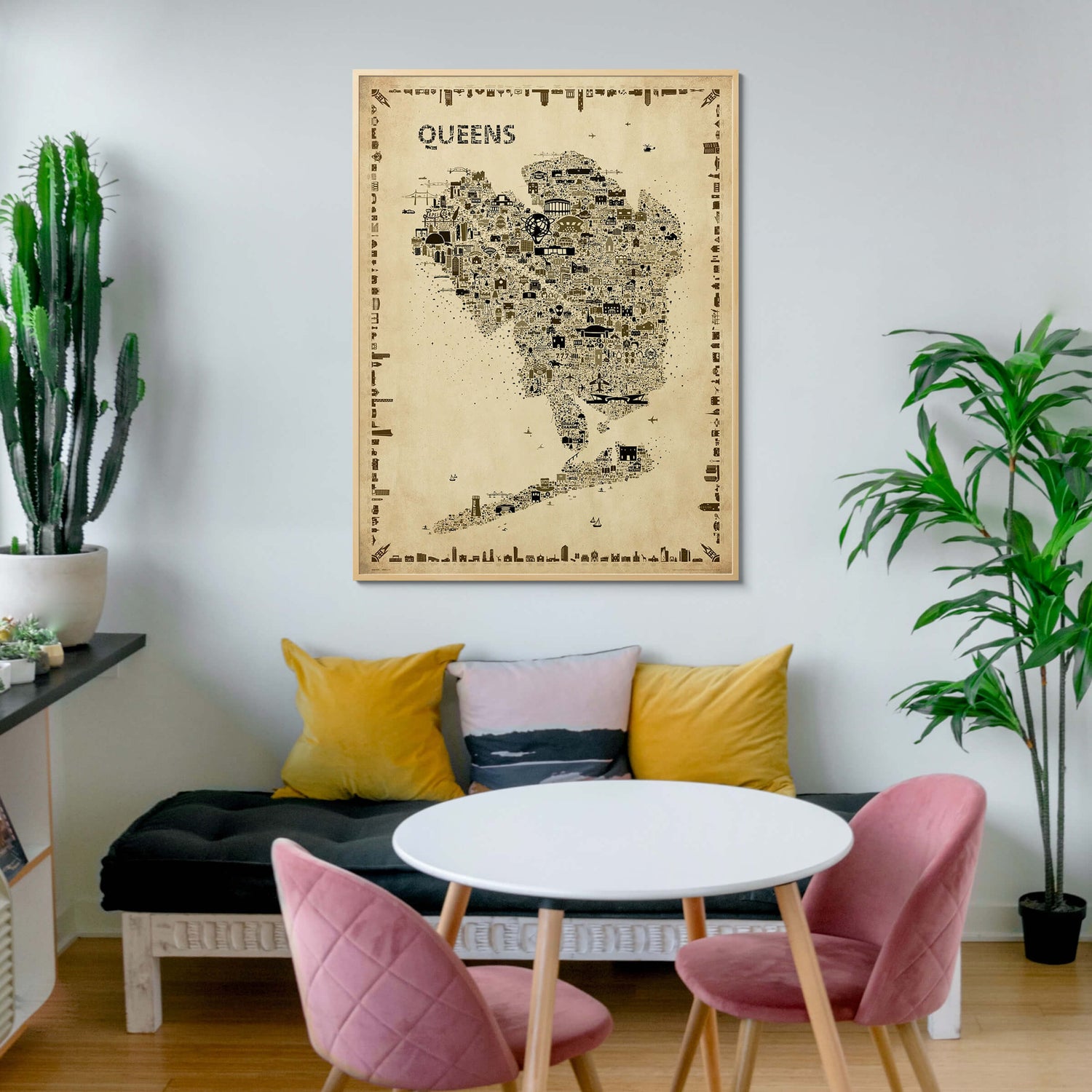 Iconic Queens Antique Edition Poster in a natural wood frame, styled in a youthful entryway with pink velvet chairs, modern round table, houseplants, and cozy sofa. Sepia-toned NYC map wall art with vintage flair.
