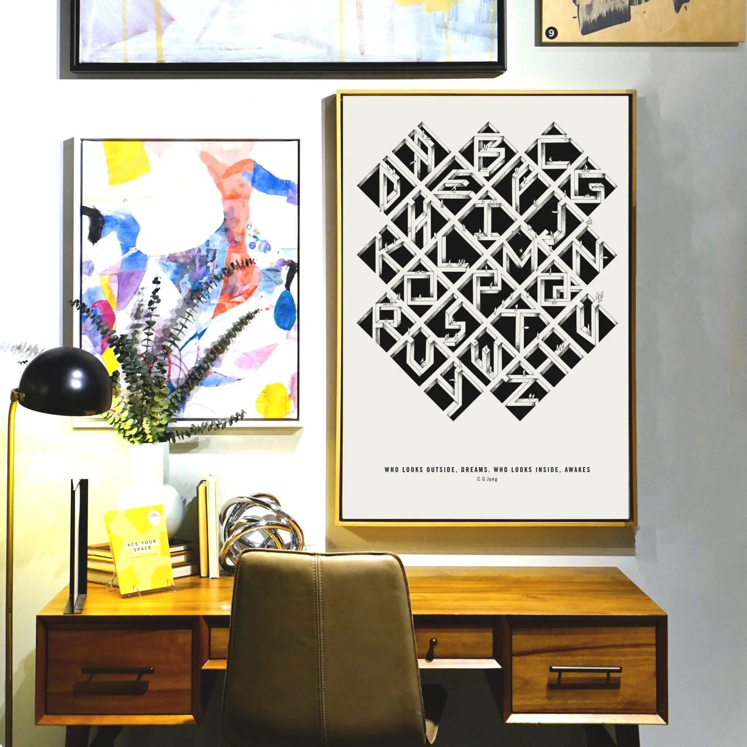 Alfalfabet typographic poster in gold frame displayed above mid-century modern desk with colorful abstract art and black lamp