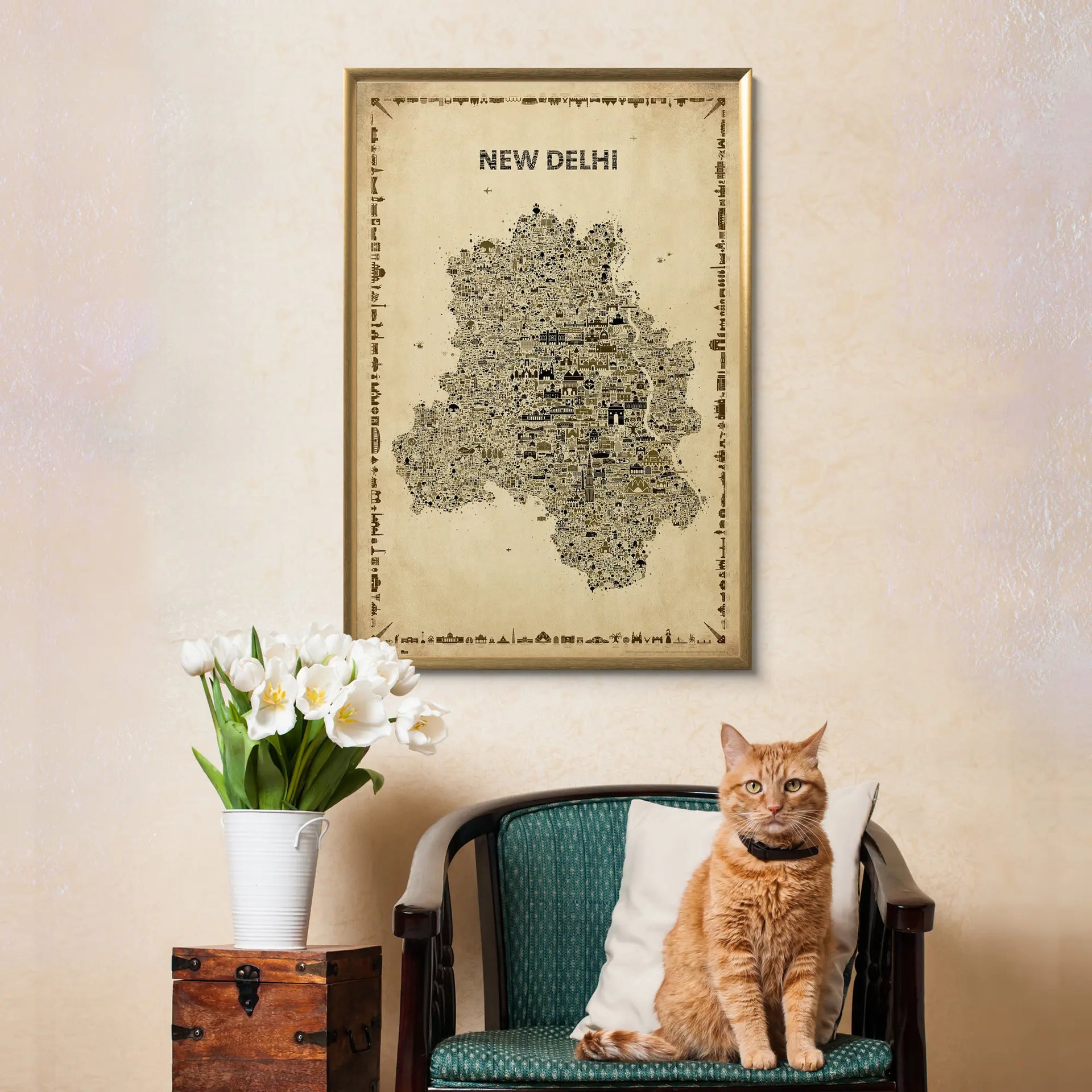 Cat sitting on a chair with a map of New Delhi framed above, against a beige wall.