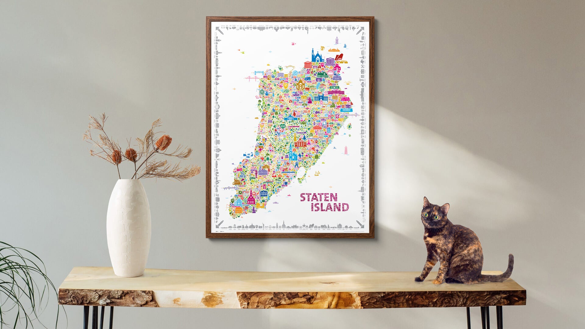 Iconic Staten Island colorful illustrated map poster in wooden frame displayed on rustic live-edge table with cat and dried flowers