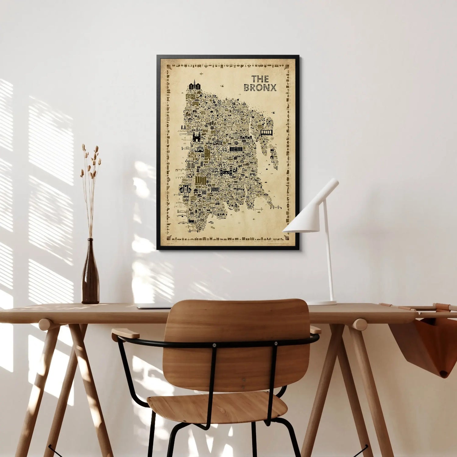 Framed map of The Bronx on a wall above a wooden desk with a chair.