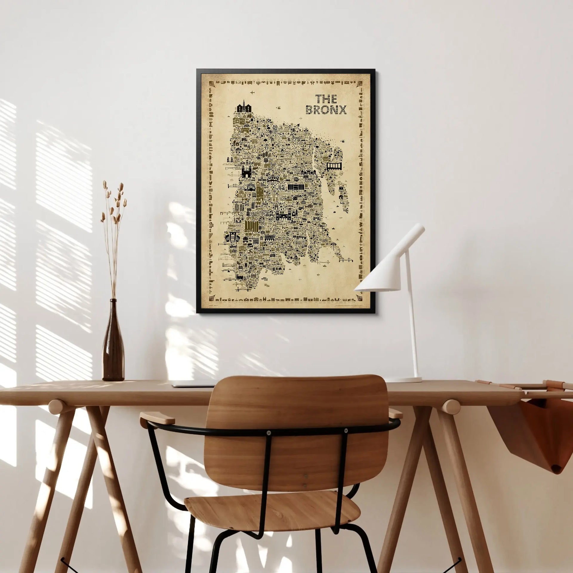Framed map of The Bronx on a wall above a wooden desk with a chair.
