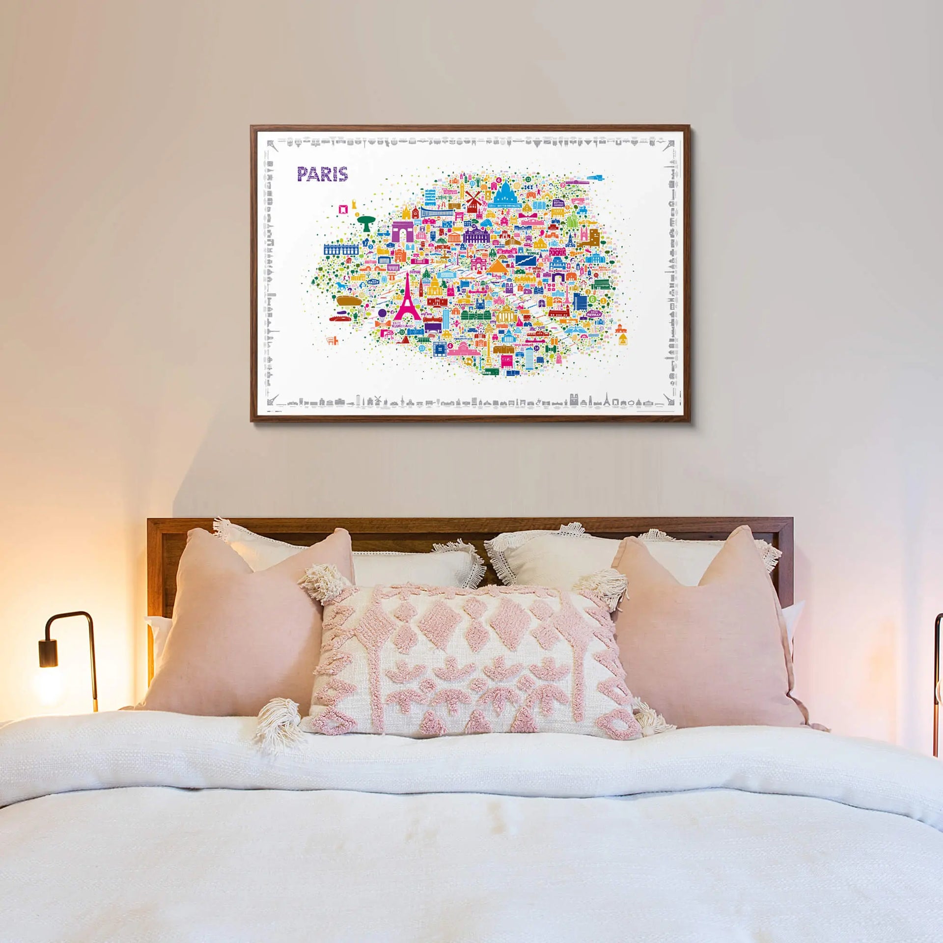Framed map of Paris on a wall above a bed with pink bedding.
