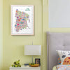 Colorful map of The Bronx on a wall above a nightstand with a lamp and decorative items.