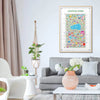 Central Park colorful illustrated map art print framed in light wood, hanging above a modern grey sofa with white and green decor — bright contemporary living room interior by Alfalfa New York.