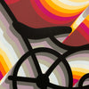 Close-up of East LA Lowrider Bike showing the black banana seat, the wheel hub, and shadows made of stacked gray and lilac stripes