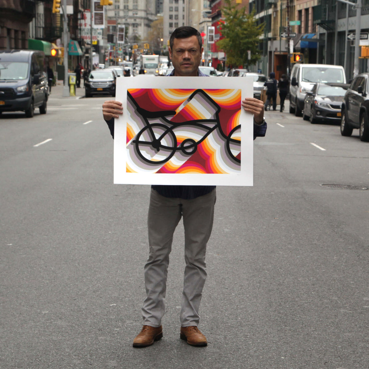 Rafael Esquer holding the full sheet of East LA Lowrider Bike, an unframed screenprint, on a New York street to show its size