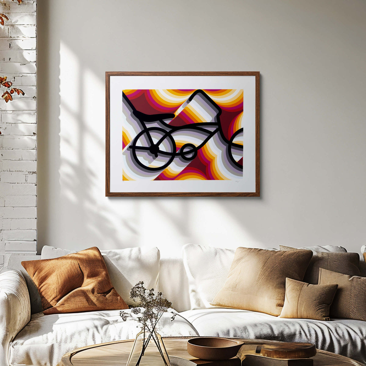 East LA Lowrider Bike screenprint in a dark wood frame on a sunlit wall above a cream sofa with rust and tan cushions