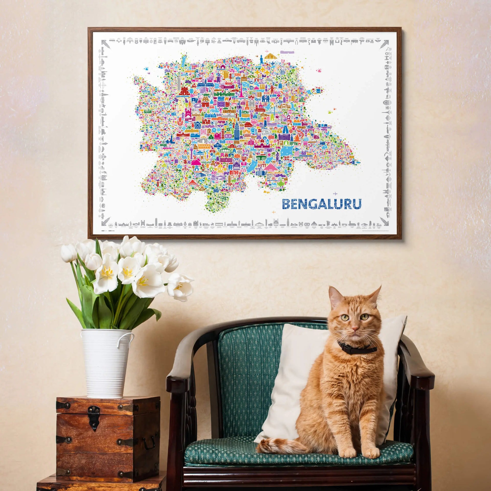 Framed map of Bangalore above a cat sitting on a chair with flowers and a wooden box.