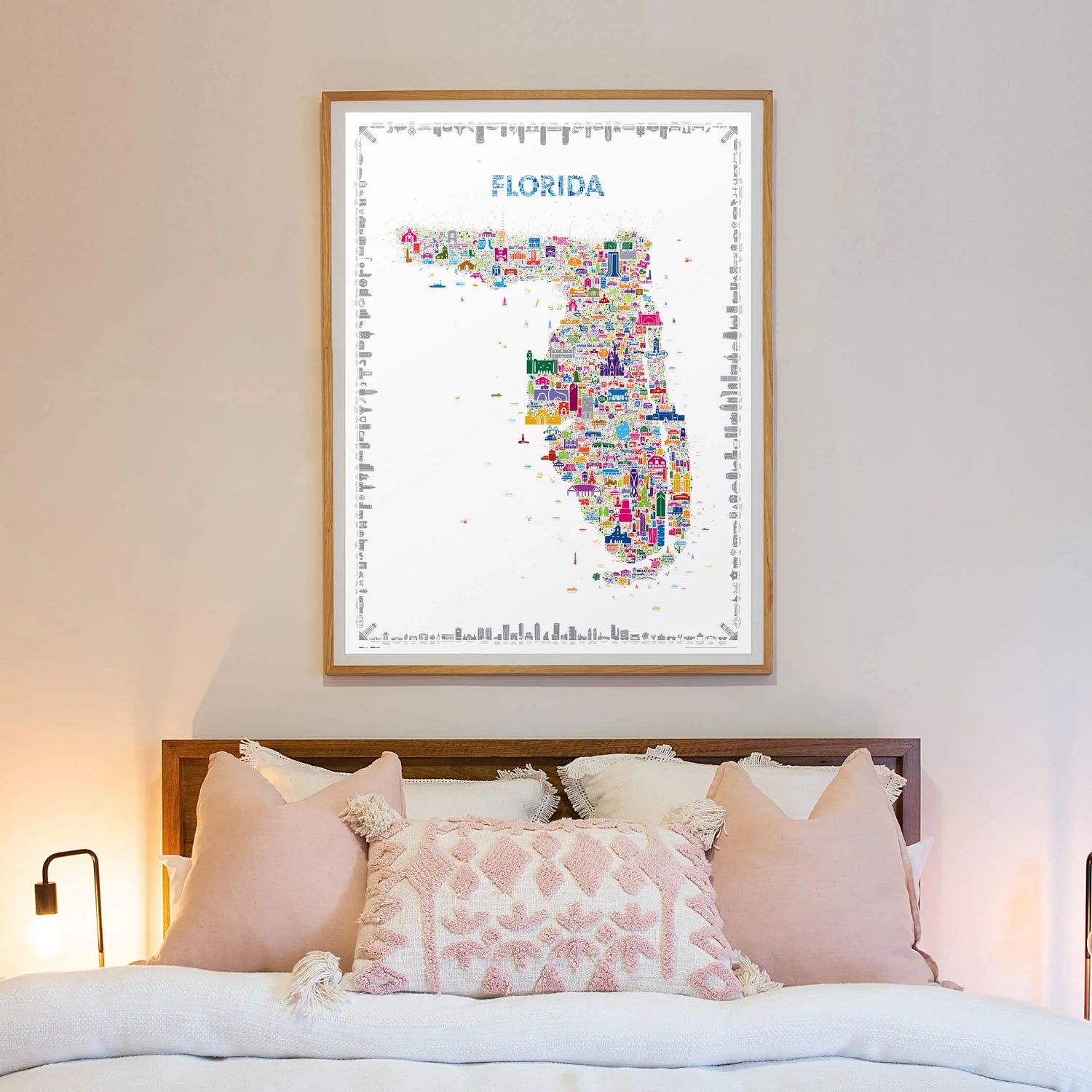 Framed map of Florida with colorful cities on a wall above a bed.