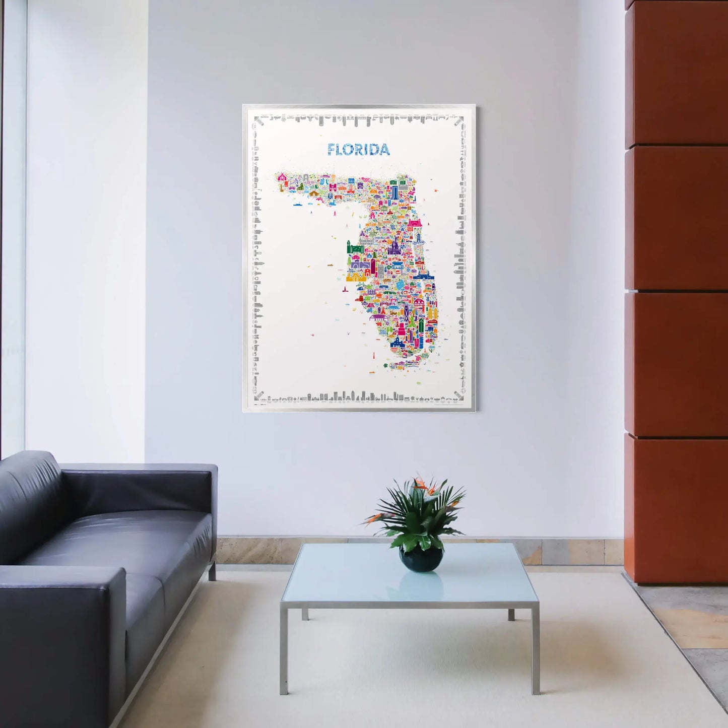 Living room with a colorful Florida map on the wall, a gray sofa, and a glass table with a plant.