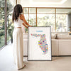 Large Iconic Florida map poster in black frame styled in modern home with natural light and person interacting, contemporary travel wall art