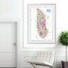 Framed Alfalfa New York illustrated map poster of Manhattan displayed on a white wall in a modern living room with a minimalist chair and indoor plant.