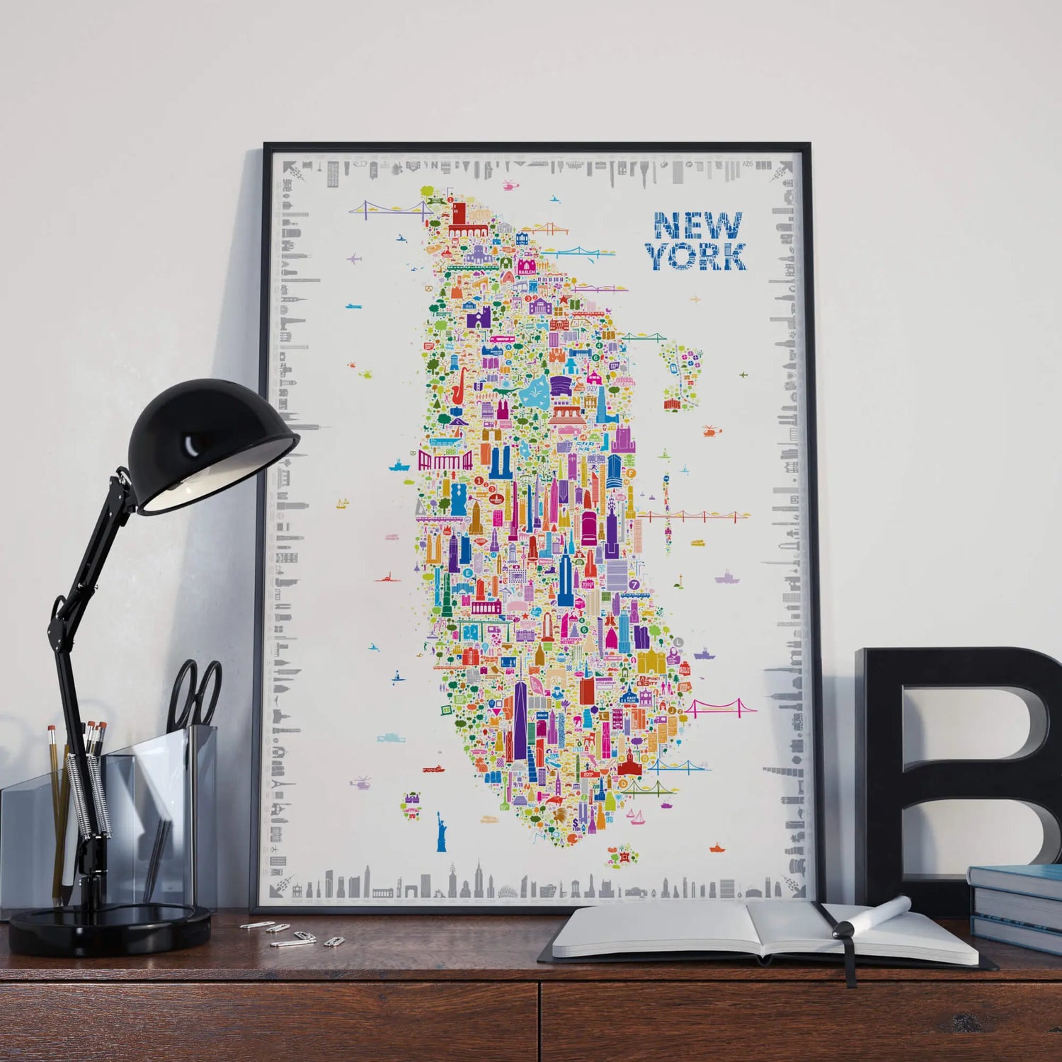 Colorful New York map poster on a desk with a lamp and books.