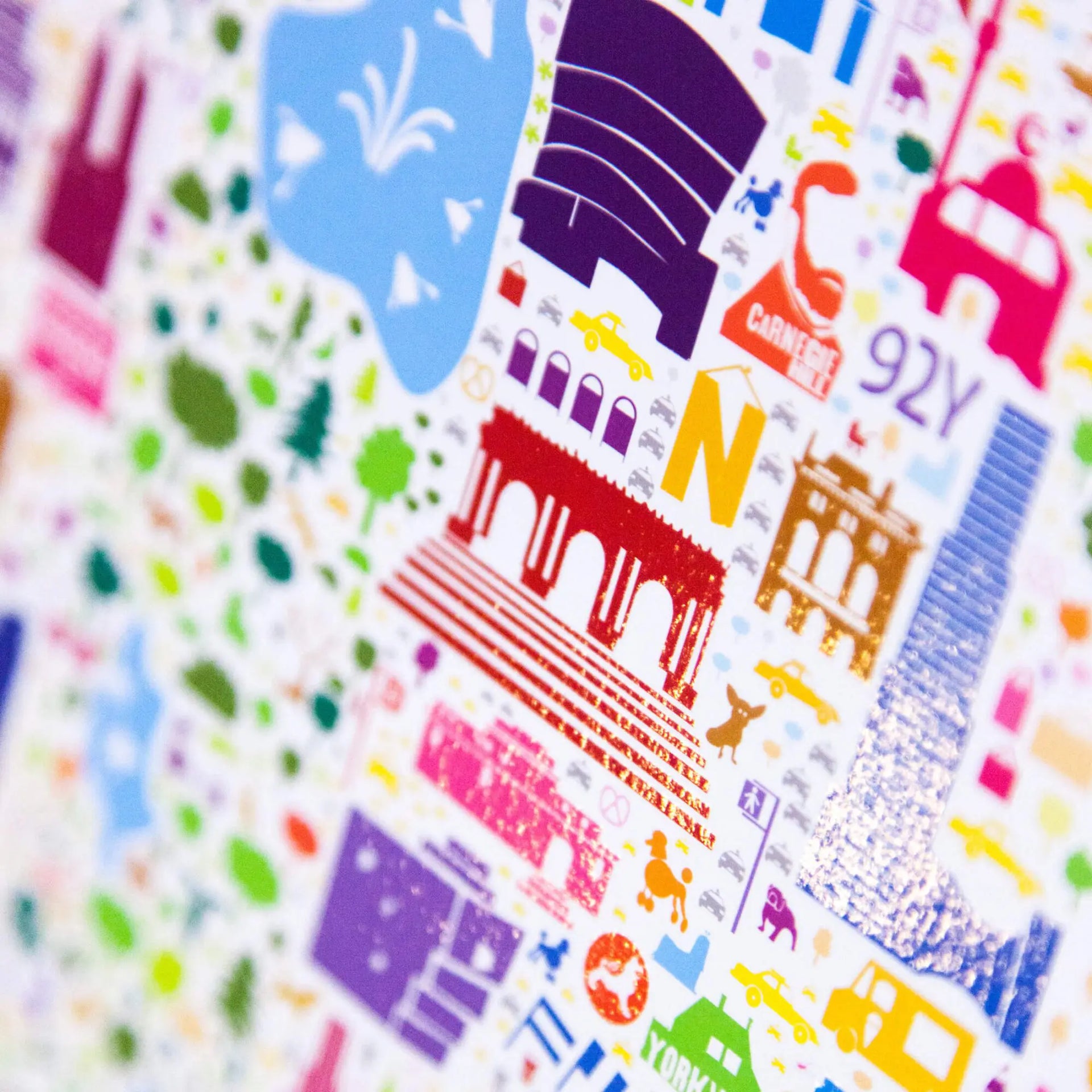 Close-up macro shot of Alfalfa New York illustrated map poster showing colorful details of New York landmarks like the Guggenheim Museum and Washington Square Arch with glossy print texture.