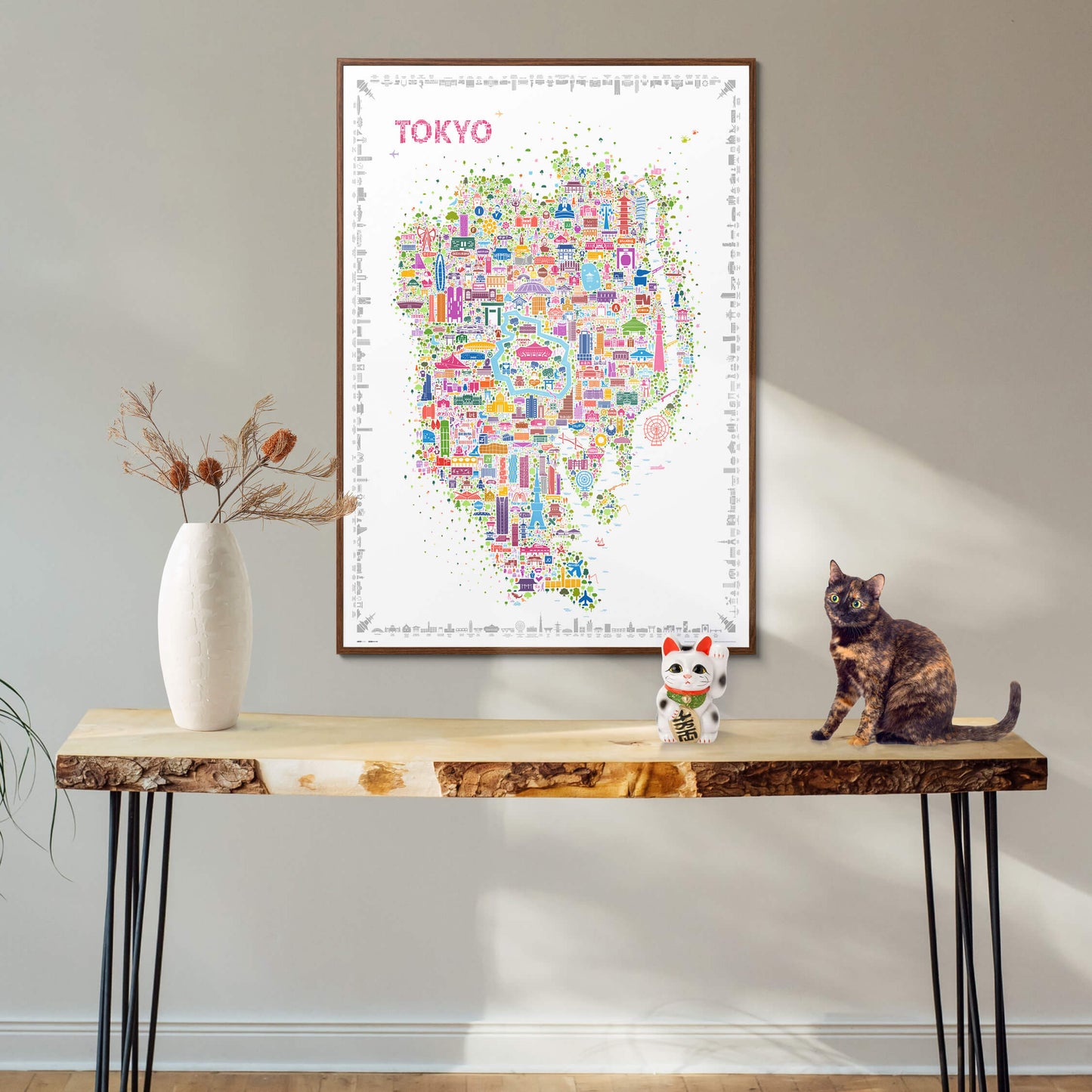 Iconic Tokyo poster in a dark wood frame above a console table featuring a Japanese lucky cat and a tortoiseshell cat, warm modern home décor with cultural charm
