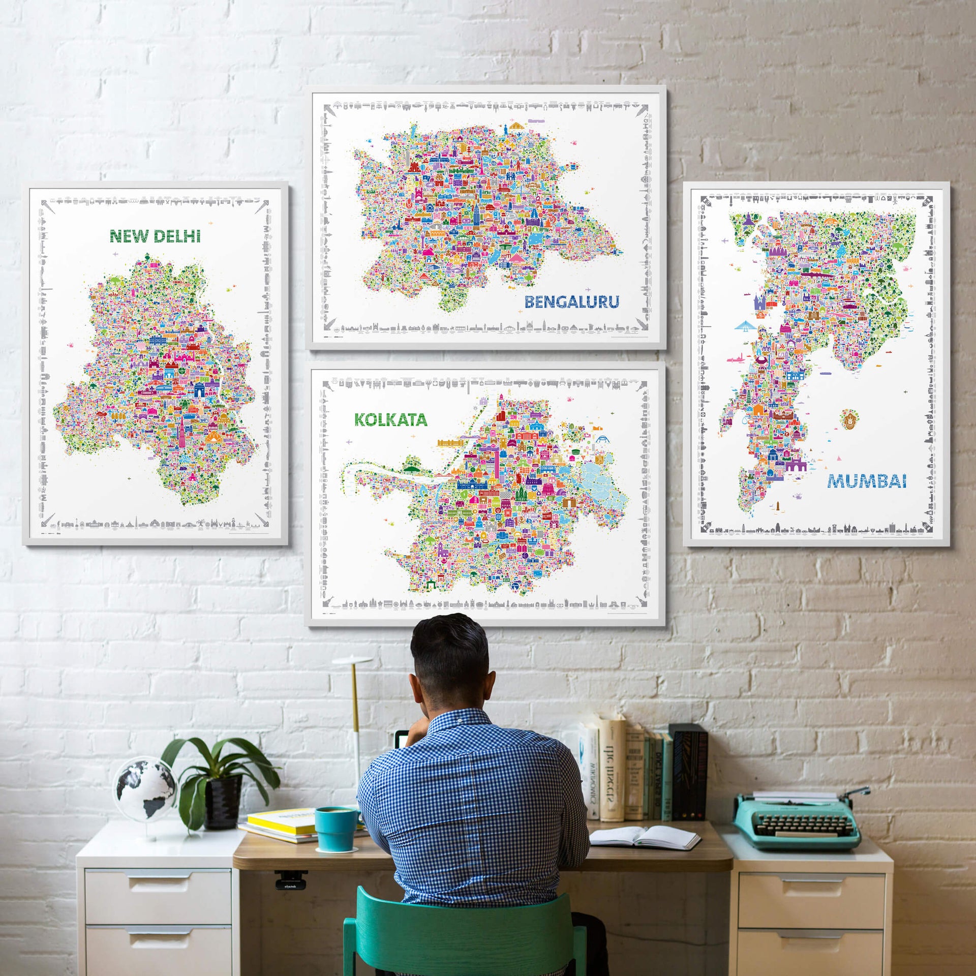Person sitting at a desk with colorful city maps on a white brick wall