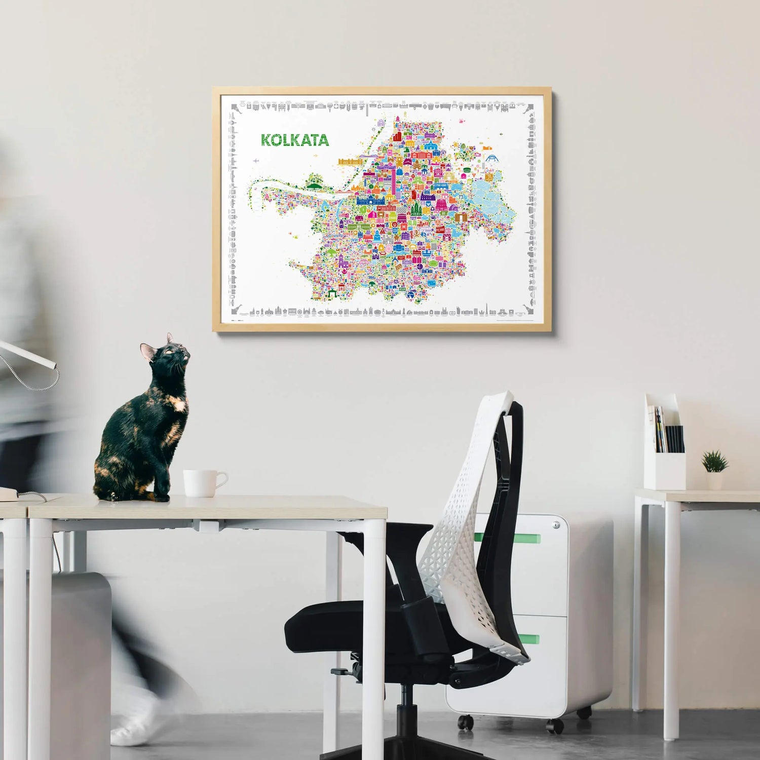 Colorful map of Kolkata framed on a wall above a desk with office furniture.