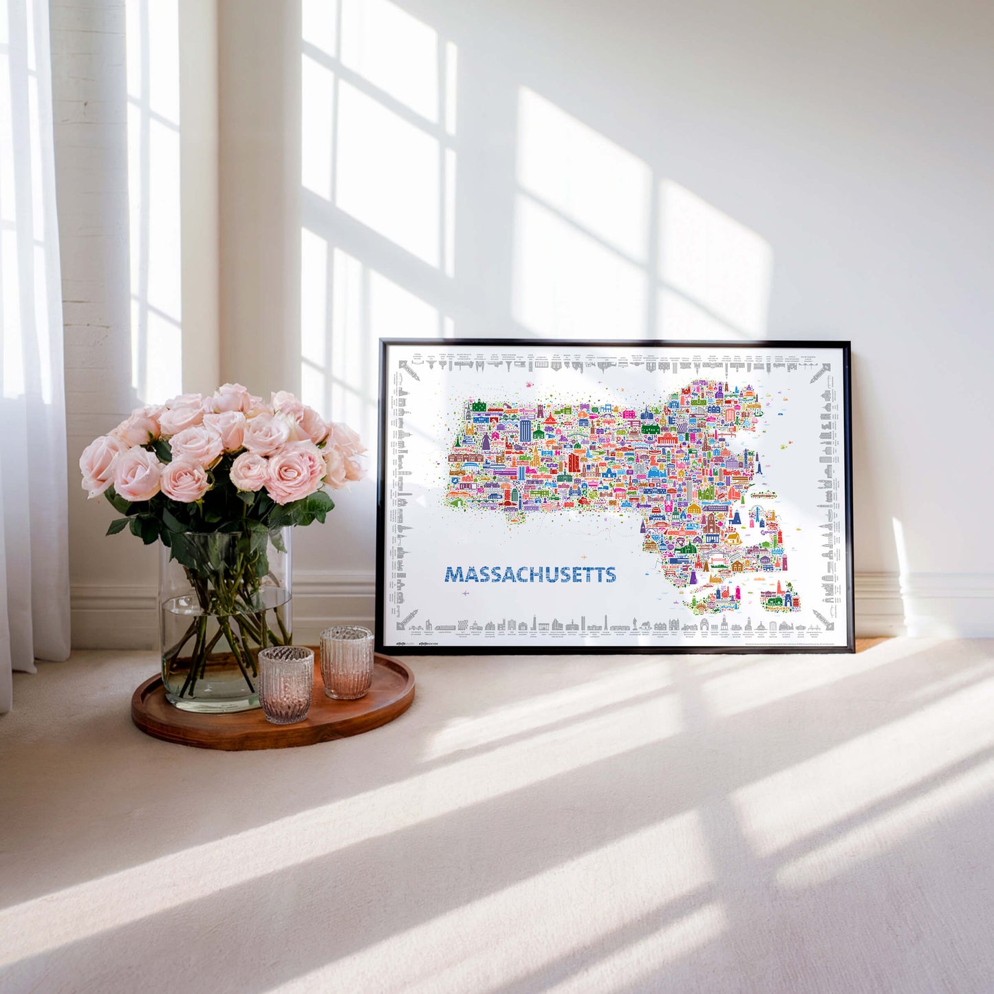 Modern Massachusetts illustrated map poster framed as colorful wall art beside roses and sunlight. Contemporary travel map artwork highlighting Boston, Cape Cod, and New England landmarks in vibrant designer style.