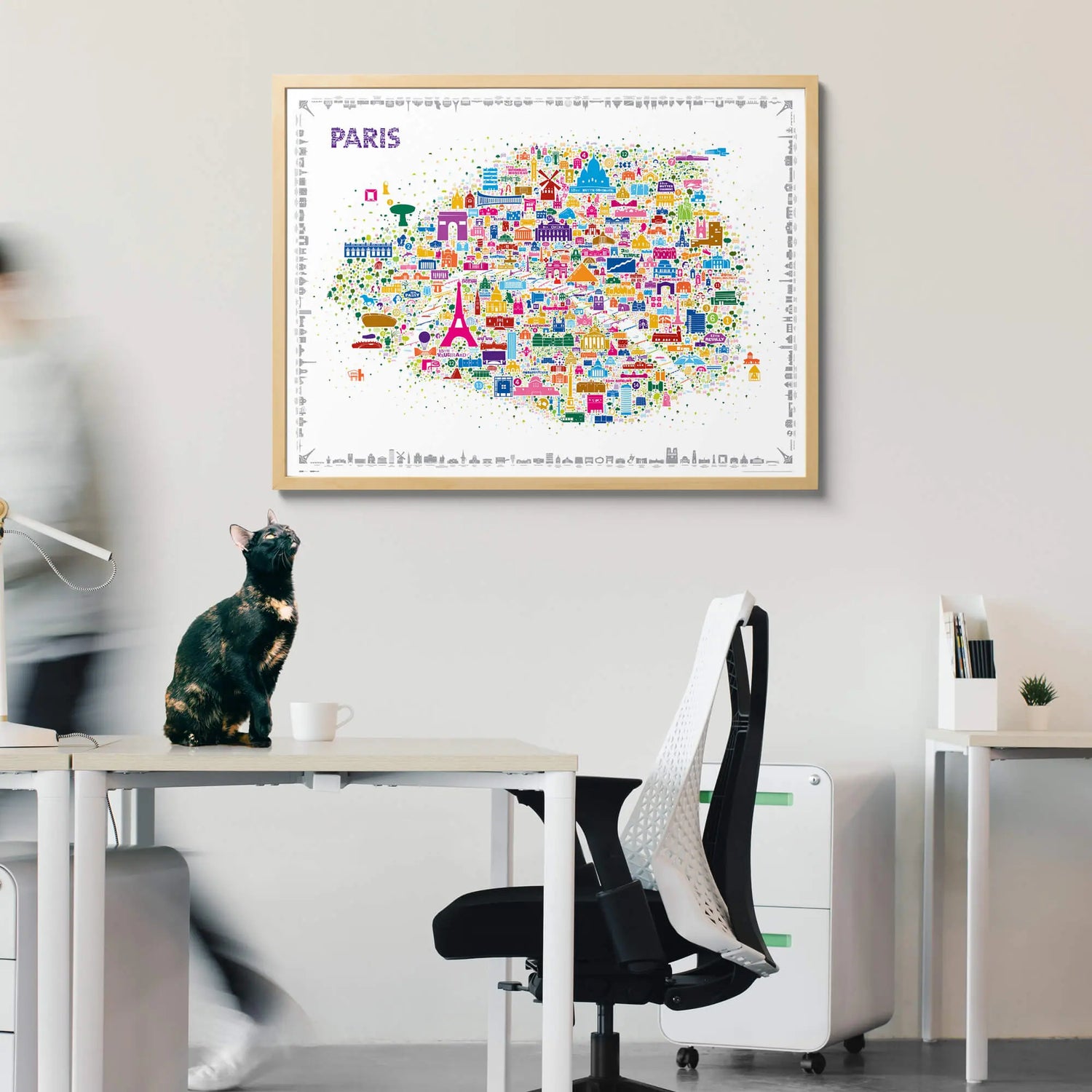 Colorful map of Paris on a wall above a desk with office furniture.