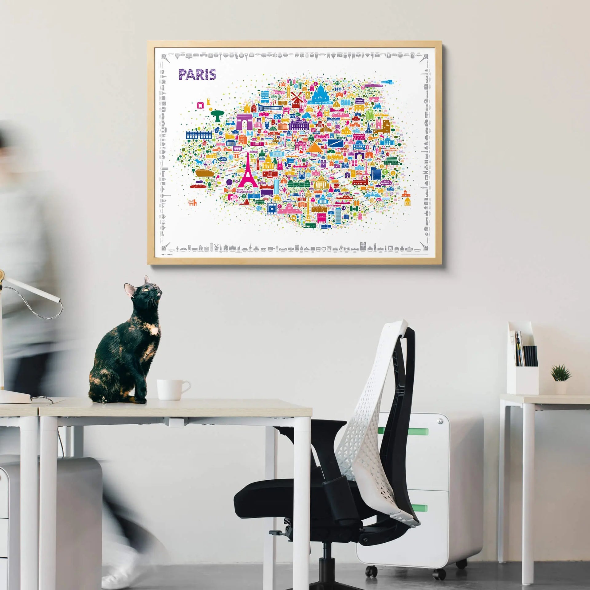Colorful map of Paris on a wall above a desk with office furniture.