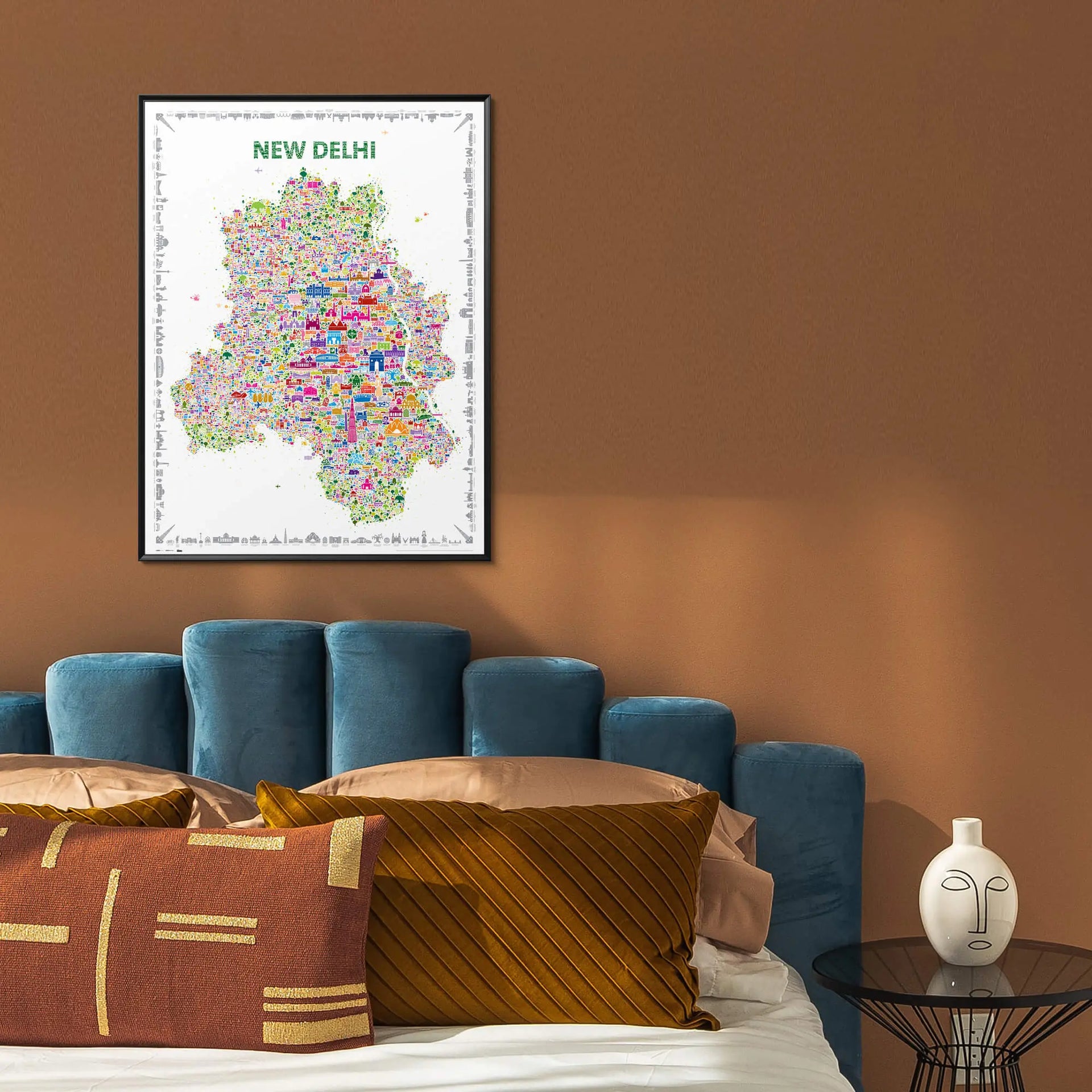 Framed map of New Delhi on a wall above a blue sofa with decorative pillows.
