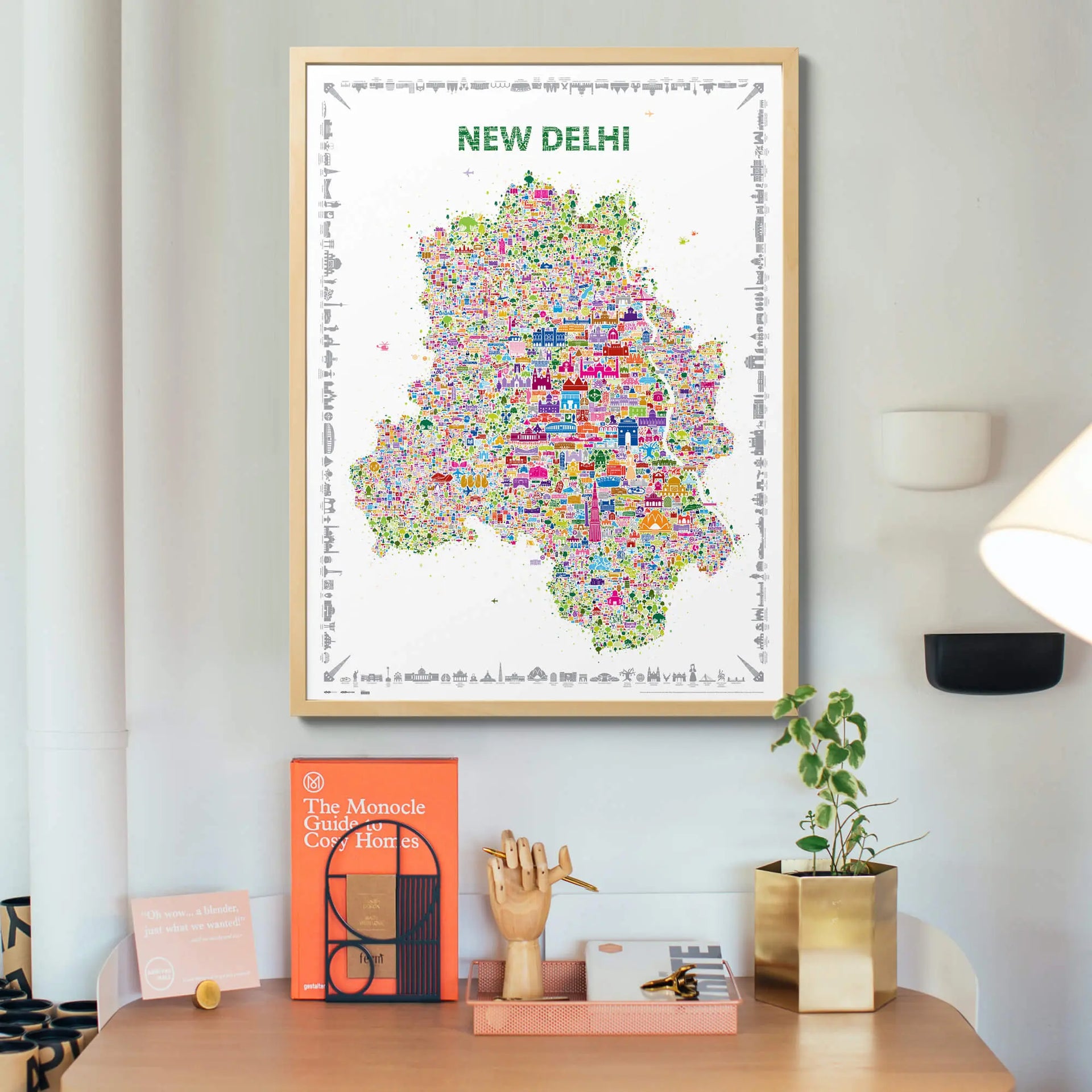 Framed map of New Delhi on a wall above a desk with decor items.