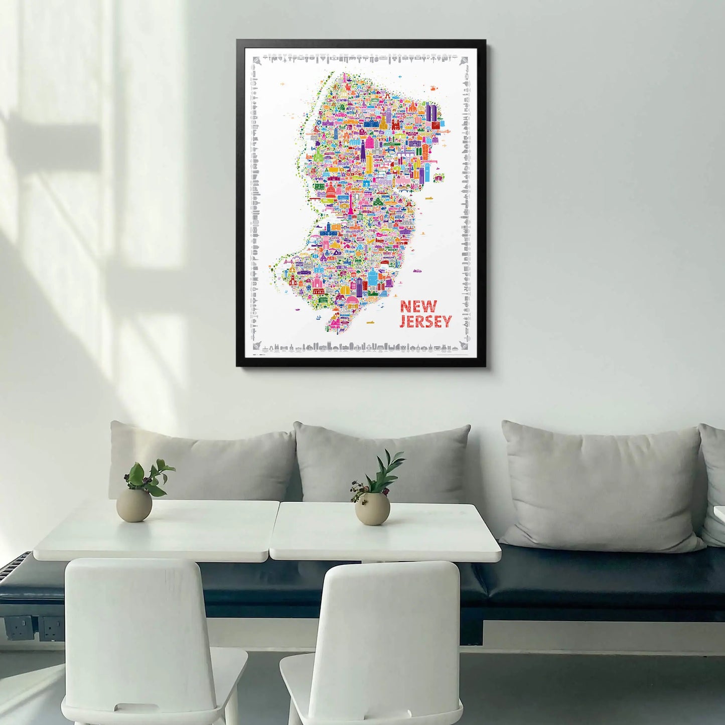 Framed New Jersey city map art print displayed in a bright modern dining space — colorful wall art in black wood frame, premium home decor by Alfalfa New York.