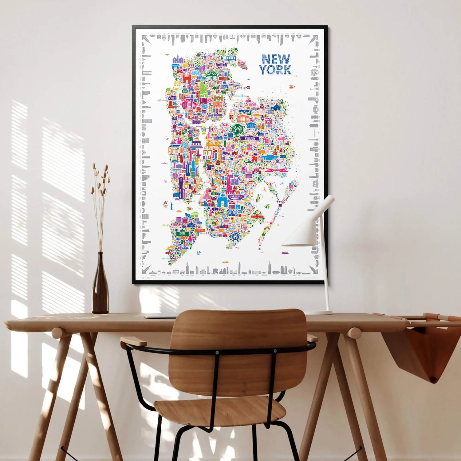 Colorful New York map poster on a wall above a wooden desk with a chair.