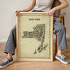Woman holding the Iconic New York State Antique Map Poster in a natural wood frame, showing real-life scale for this vintage Empire State wall art print and travel souvenir.
