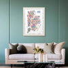 Alfalfa New York illustrated map poster of New York City framed on a teal wall above a modern sofa with neutral cushions and a glass coffee table.