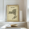 NYS Antique Map Poster in a gold frame displayed by a window with books and decorative objects, a sophisticated vintage print for classic New York State home décor.
