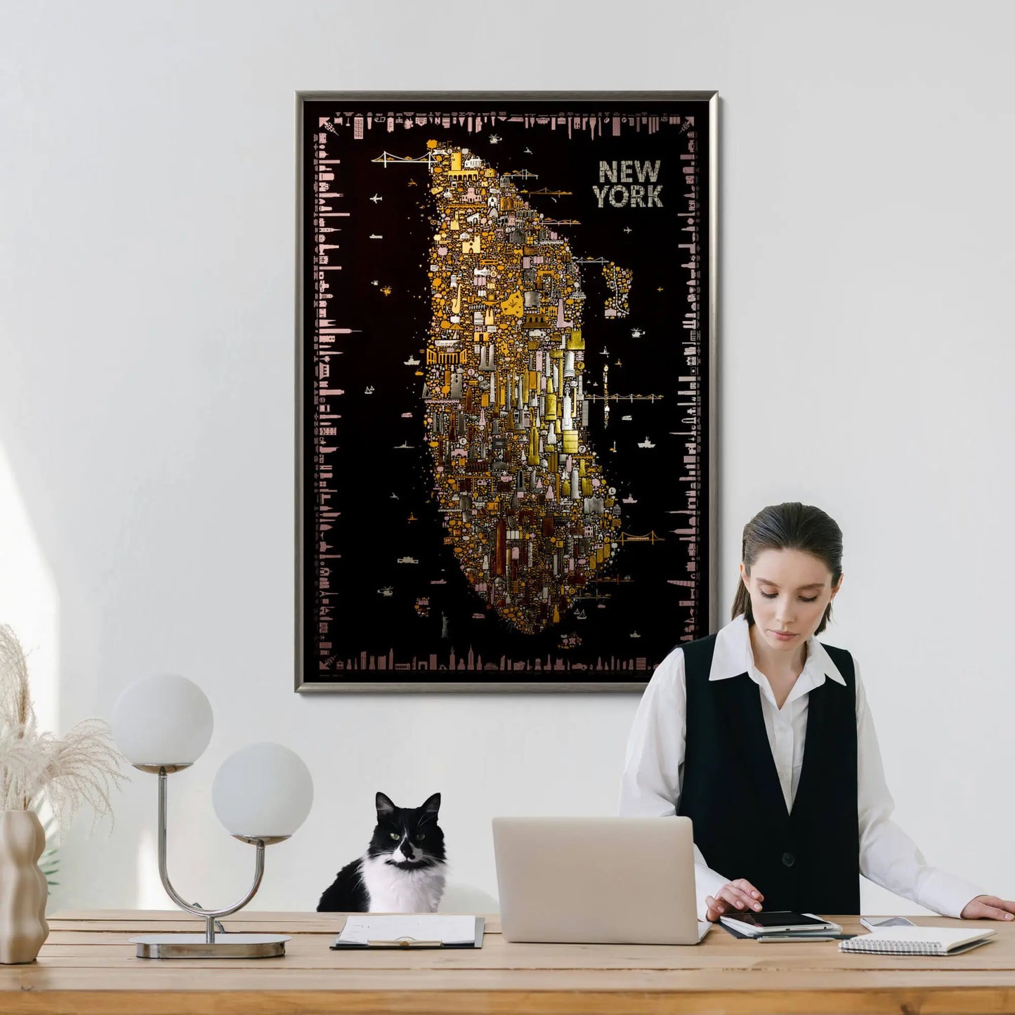 Woman working at a desk with a cat, framed map of New York on the wall.