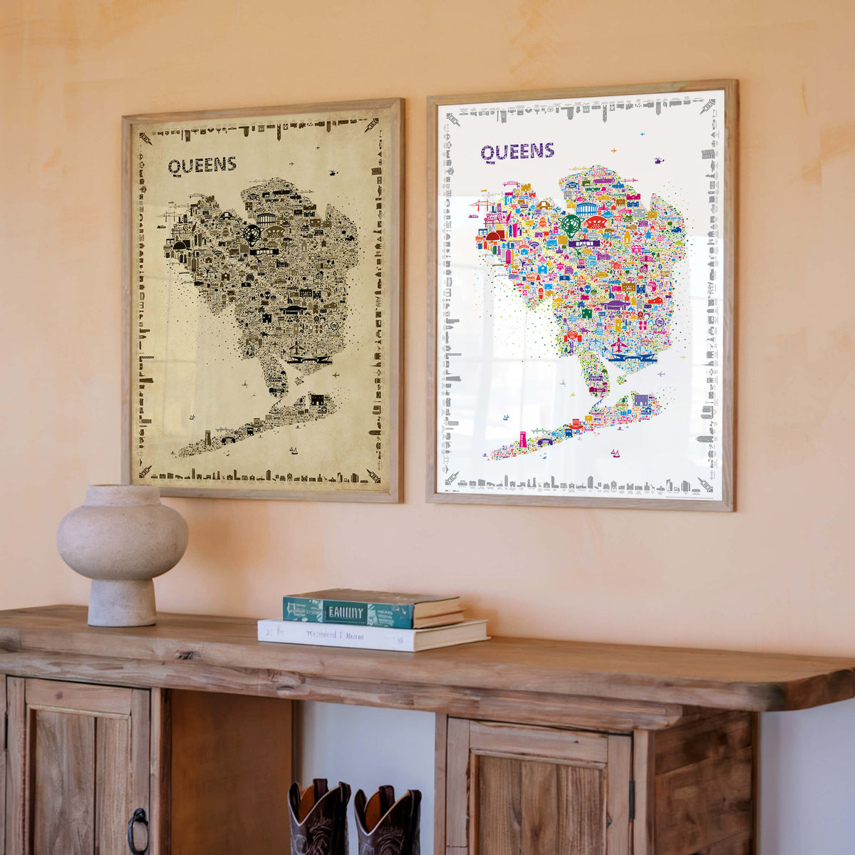 Queens New York illustrated map posters in Antique and Colorful editions displayed side by side in natural wood frames above a rustic wood console with books and a ceramic vase.