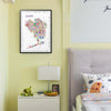 Framed Alfalfa New York Queens illustrated map poster hanging above a nightstand with a lamp and plush toy beside a cozy bed in a softly lit bedroom.