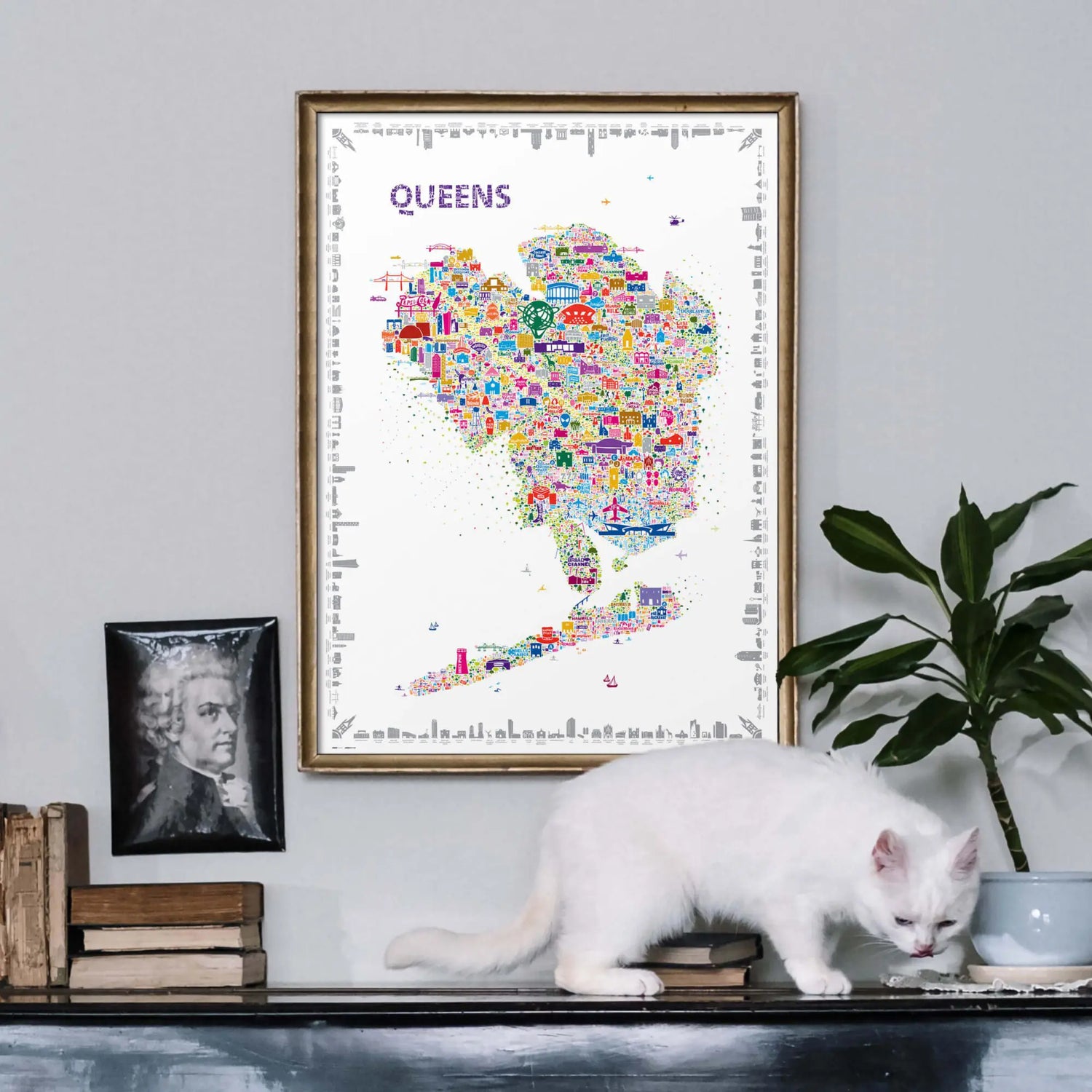 Colorful map of Queens on a wall with a white cat sitting below