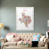 Colorful Texas map on a wall above a beige sofa with decorative pillows and a coffee table.