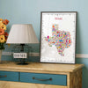 Colorful Texas illustrated map poster in a dark frame displayed on a wooden dresser next to a table lamp and flowers.