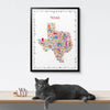 Framed map of Texas with colorful icons, a cat lying on a surface below.
