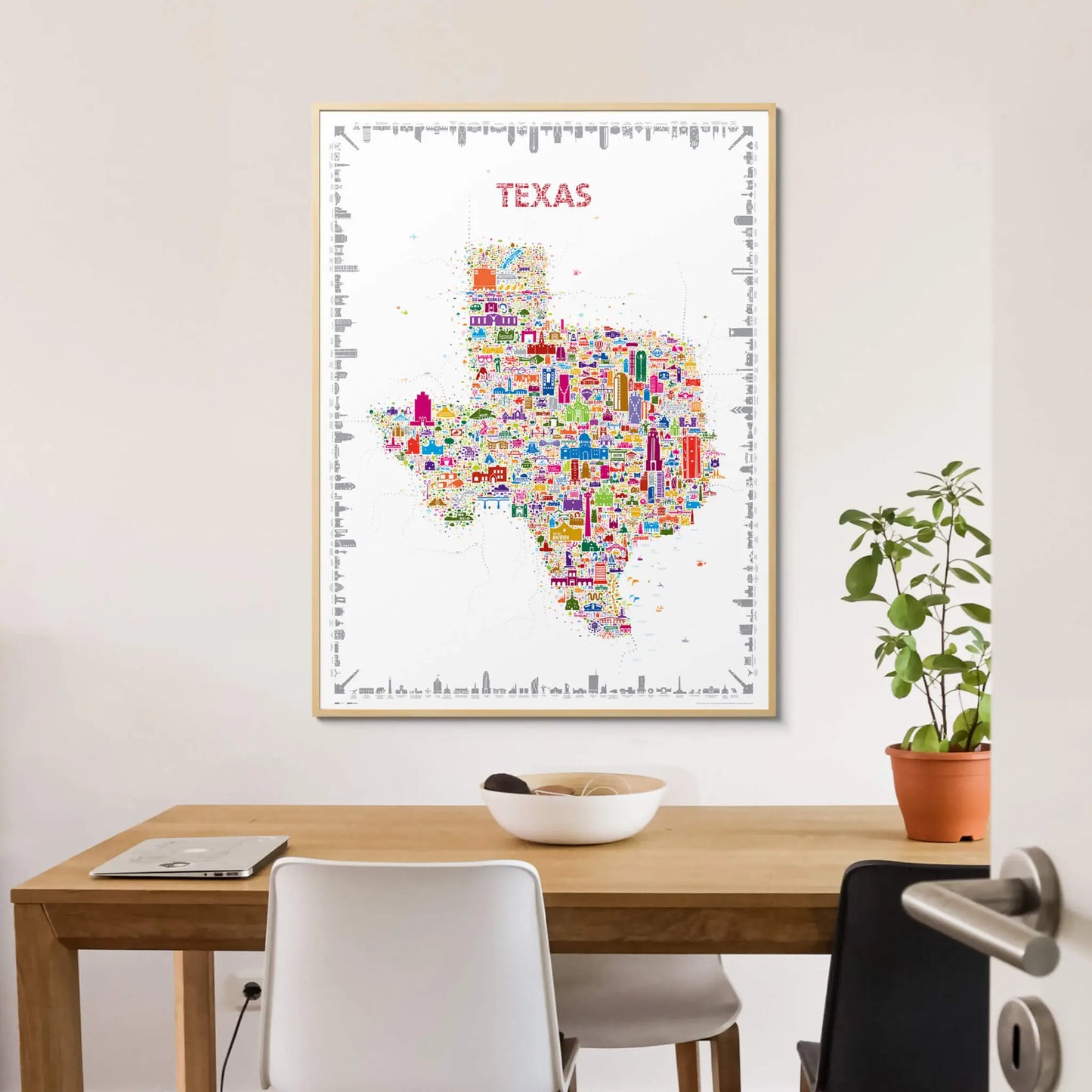 Colorful map of Texas on a wall above a wooden table with chairs.